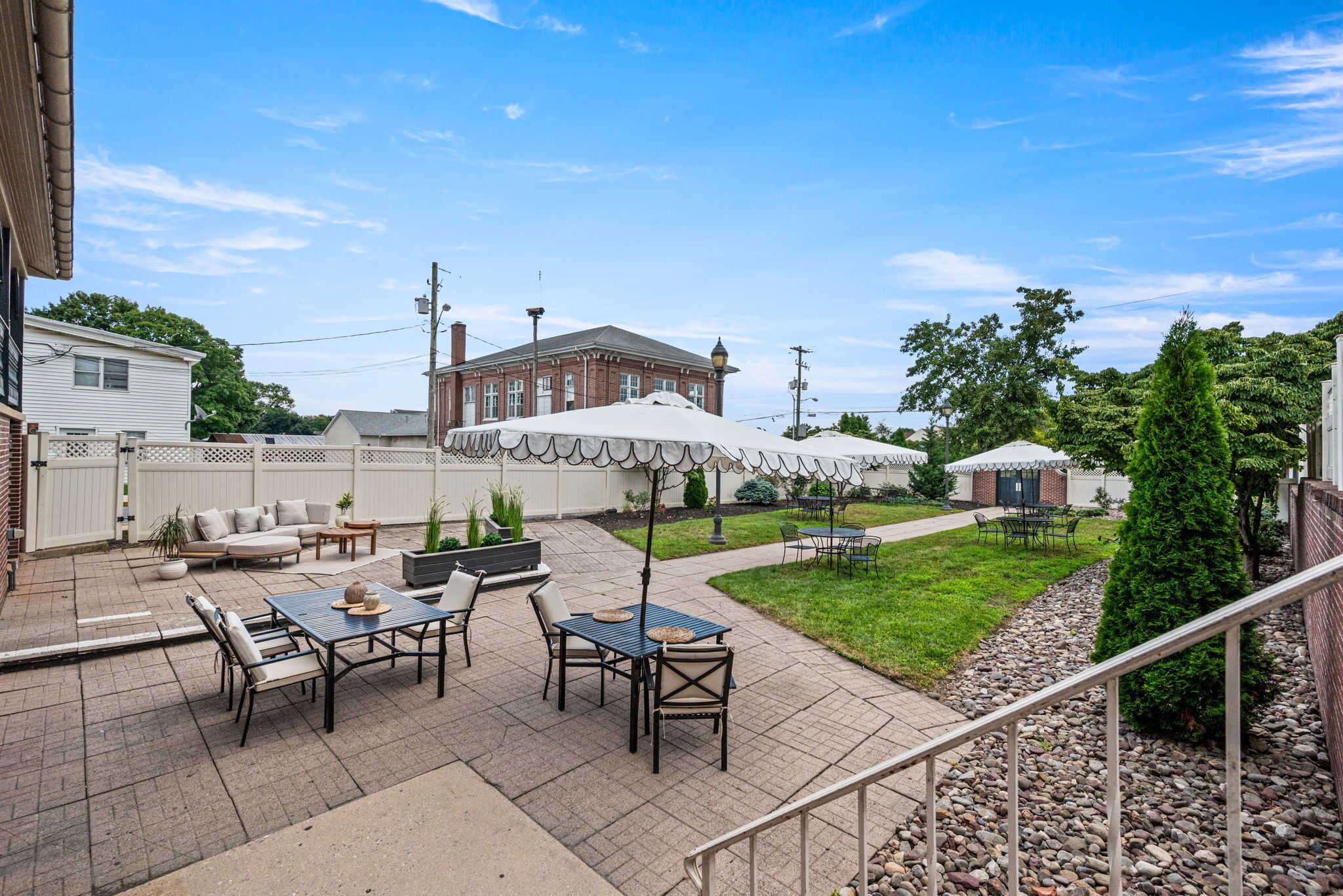 A patio area with outdoor seating, a brick building in the background, and a clear sky.