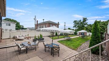 A patio area with outdoor seating, a brick building in the background, and a clear sky.