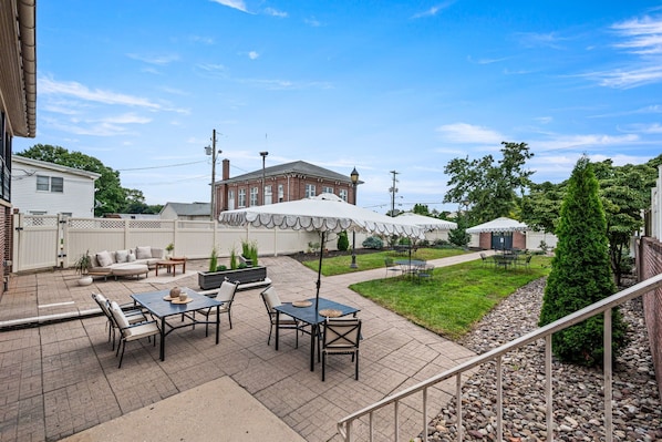 A patio area with outdoor seating, a brick building in the background, and a clear sky. - Waynebrook Inn, Est 1865 (Honey Brook)