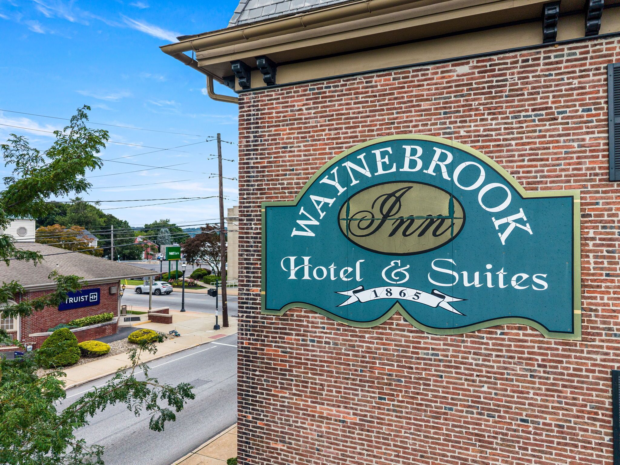 Un edificio de ladrillo con un cartel que indica Waynebrook Inn & Suites, mostrando que se trata de un hotel y suites.