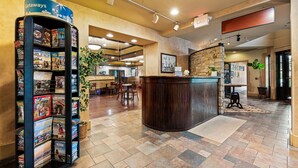 A reception area with a counter, a magazine rack, and a stone wall. - Waynebrook Inn, Est 1865 (Honey Brook)