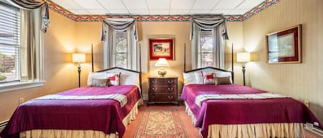A double room with two beds, a nightstand, a lamp, a painting, and a window with curtains.