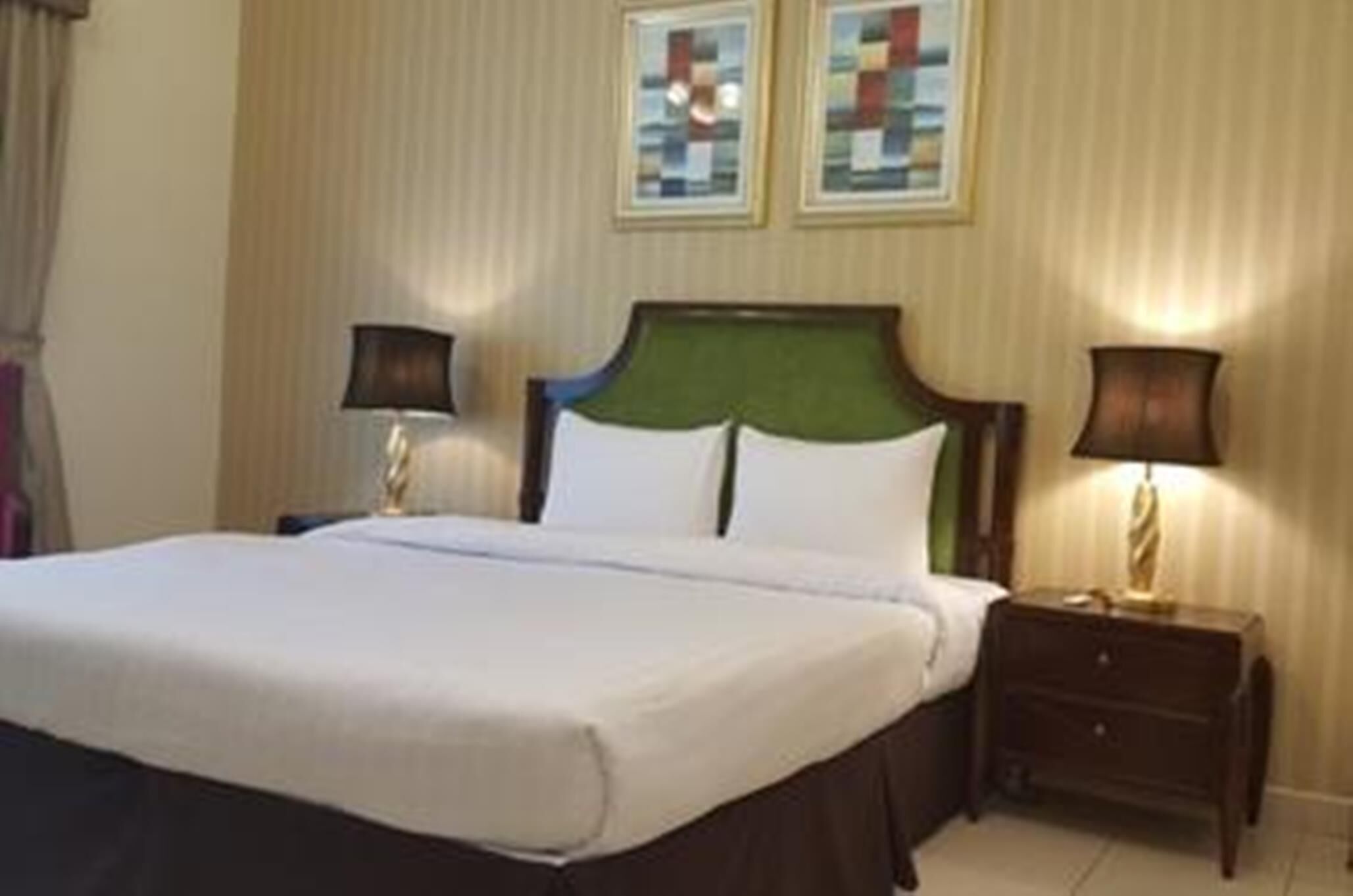Una habitación de hotel con una cama, dos mesitas de noche y dos lámparas de pared.