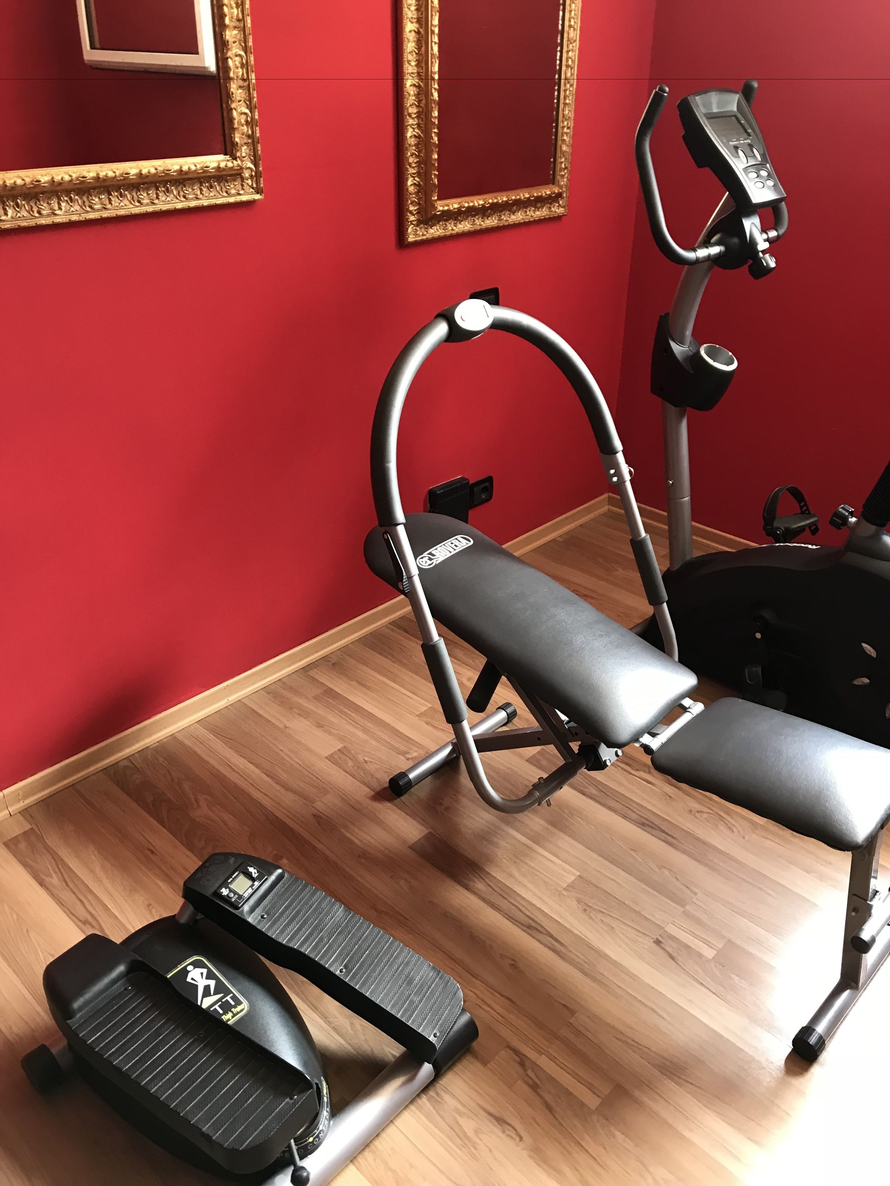 A home gym with a stationary bike, a treadmill, and a bench.