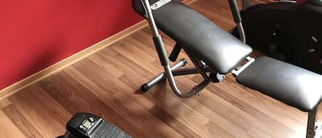 A home gym with a stationary bike, a treadmill, and a bench.