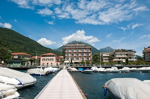 A marina with boats docked, a wooden pier, and buildings with balconies in the background.