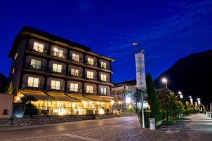 A multi-story hotel with balconies, a stone facade, and a well-lit entrance.