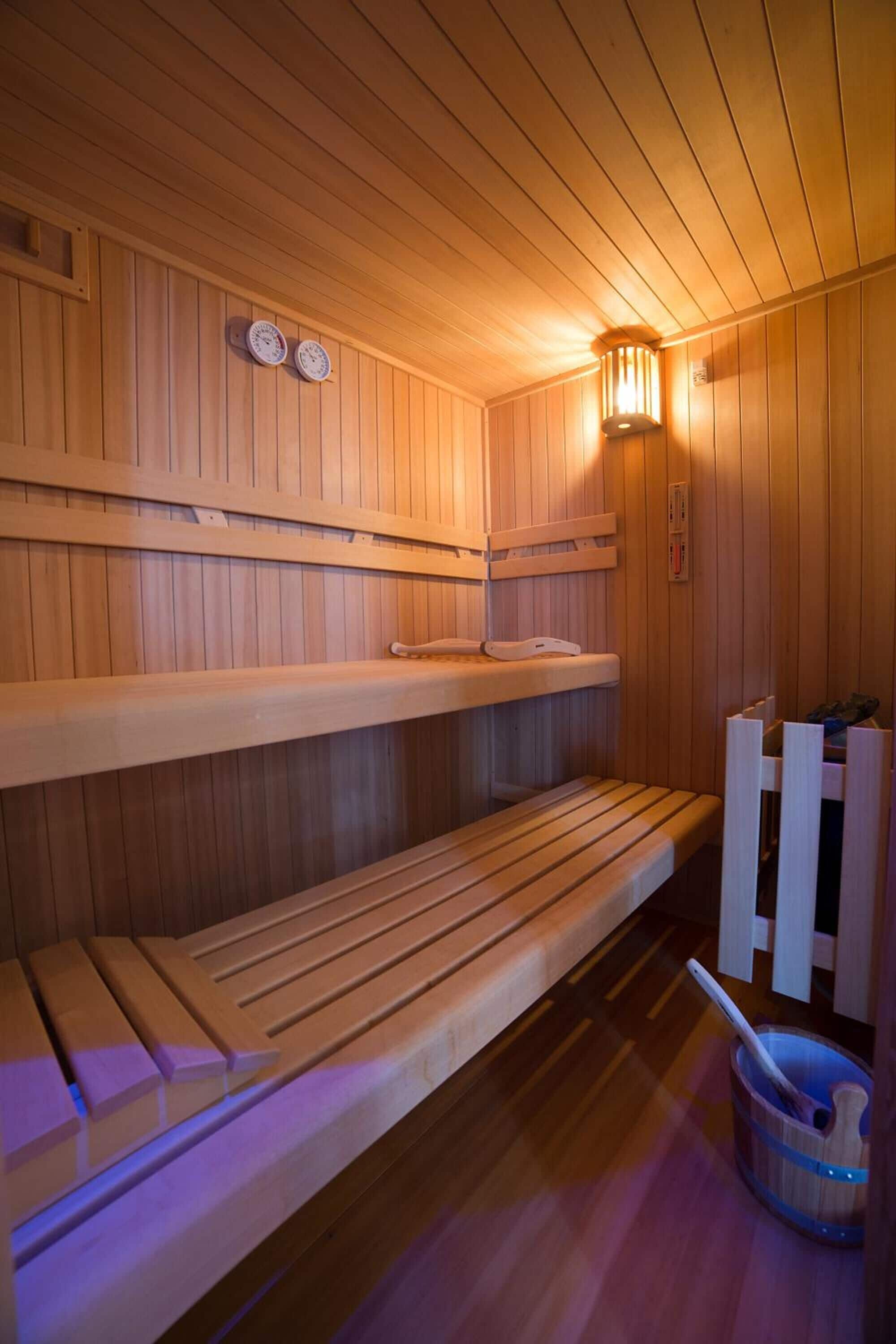 A sauna with wooden benches and a wall-mounted heater.