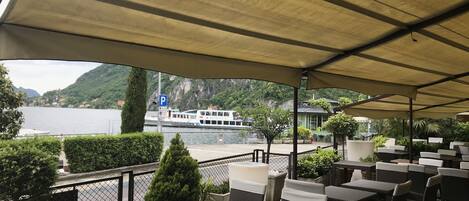 An outdoor seating area with wicker furniture and a view of a lake and mountains.