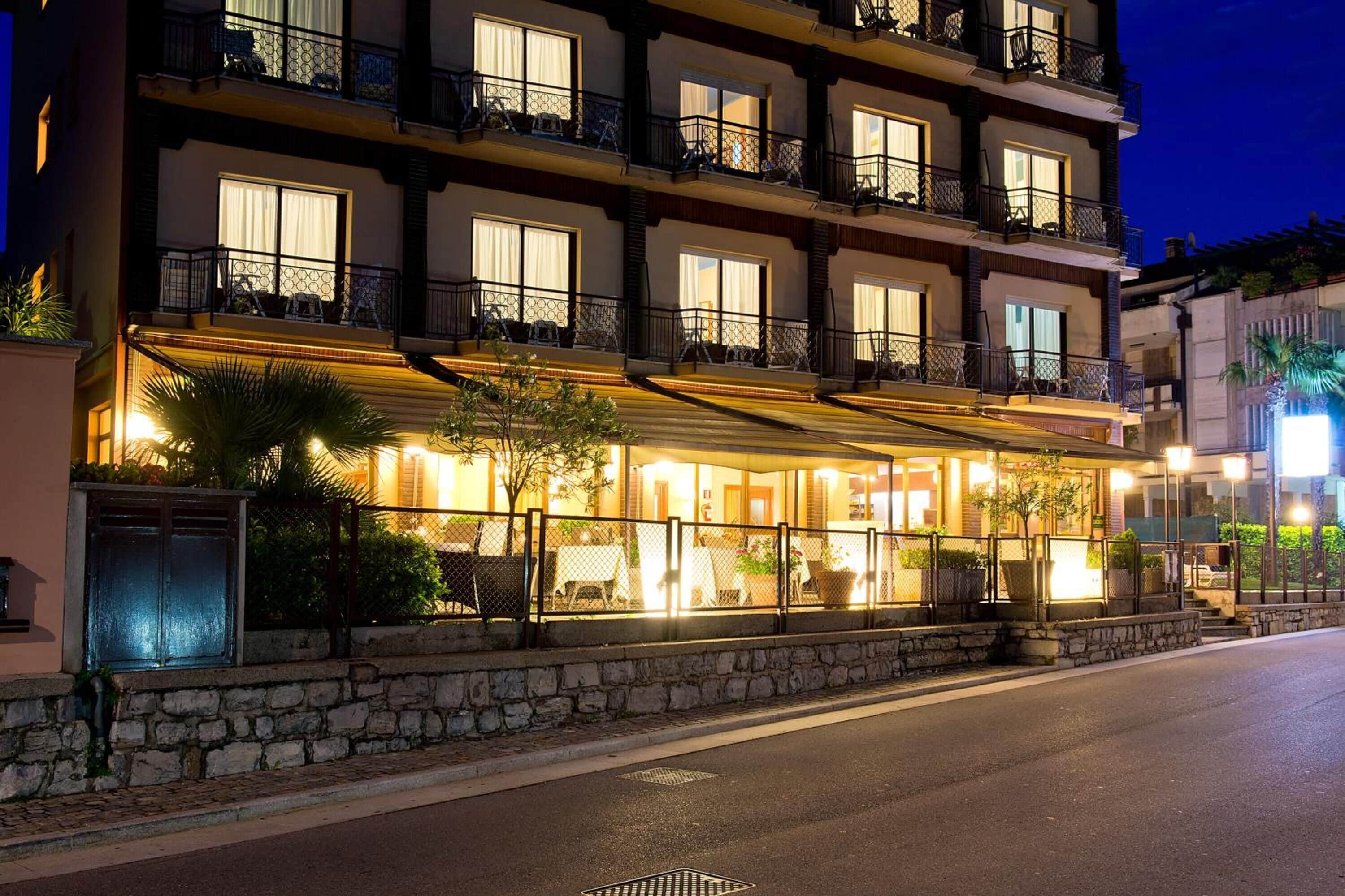 Un hôtel à plusieurs étages, doté de balcons, d’un espace extérieur couvert aménagé en coin salon et d’une façade en pierre.