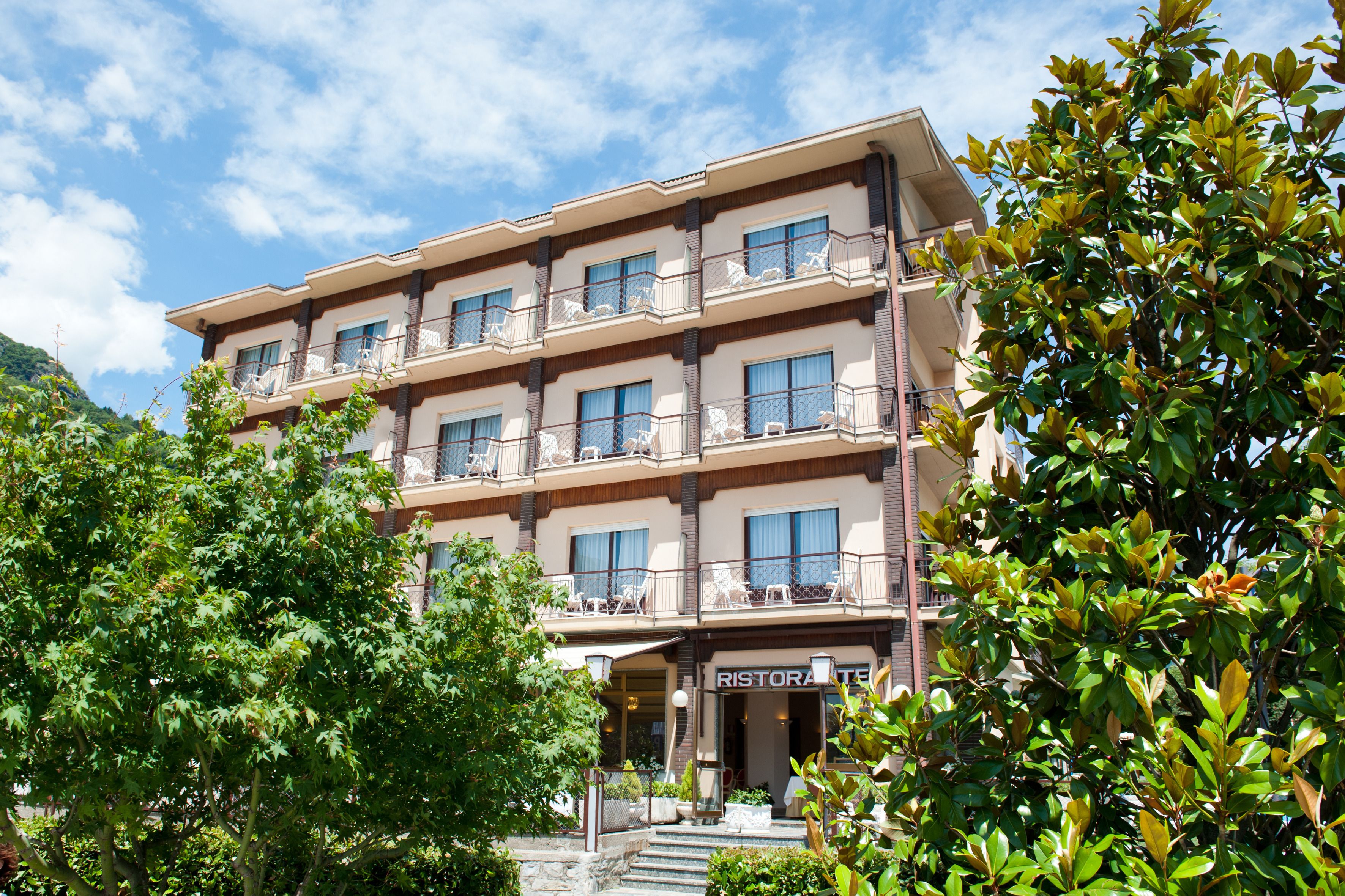 A multi-story hotel with balconies, a restaurant, and lush greenery.