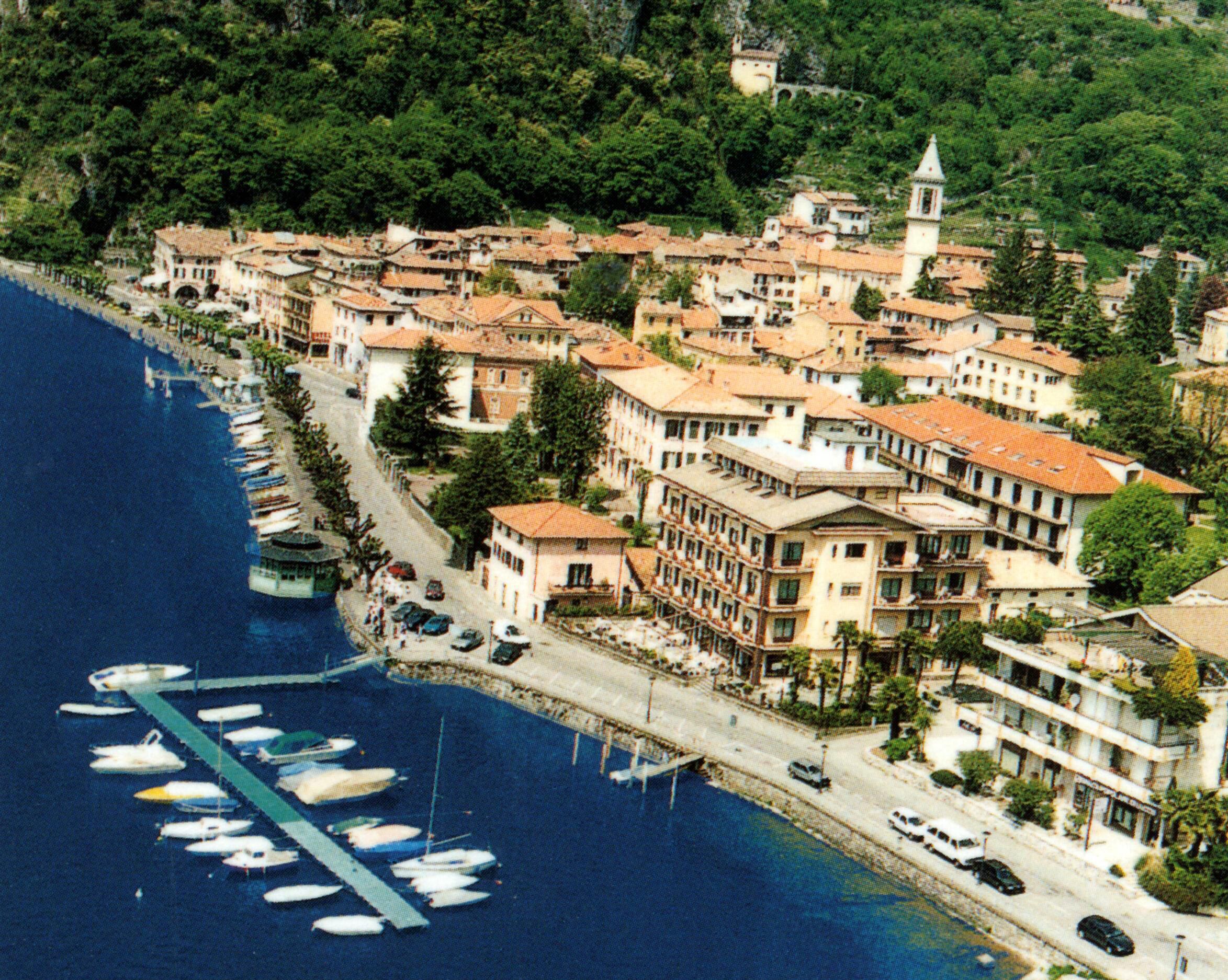 Un pueblo costero con un puerto deportivo, edificios históricos y una torre destacada.