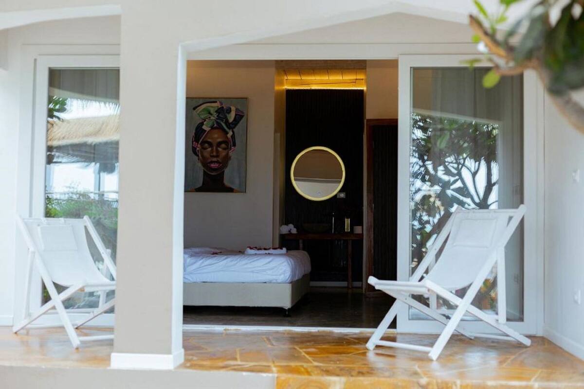 Une chambre à coucher avec un lit, un miroir rond et deux chaises blanches.