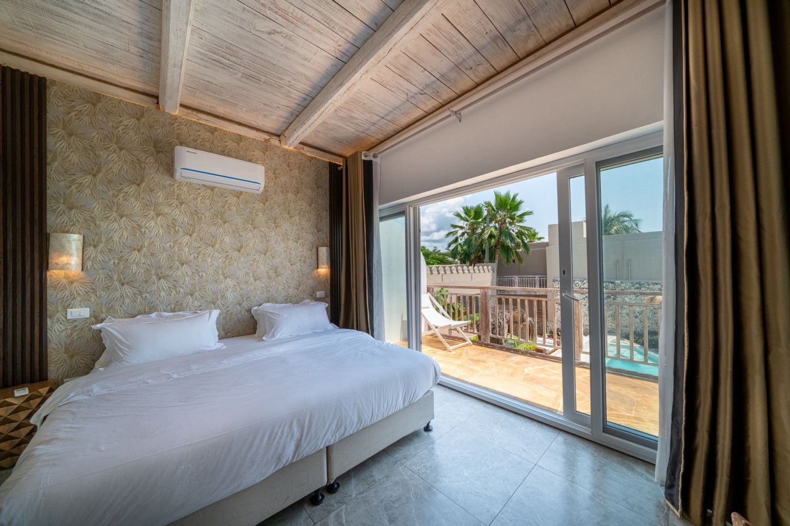 A bedroom with a large bed, a ceiling fan, and a view of a pool through a sliding glass door.