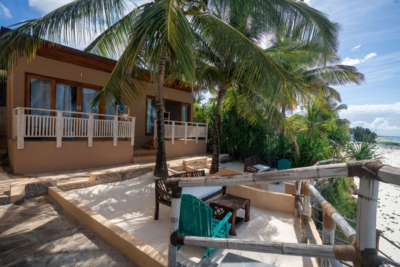 A beachfront property with a covered patio, outdoor seating, and a view of the ocean.