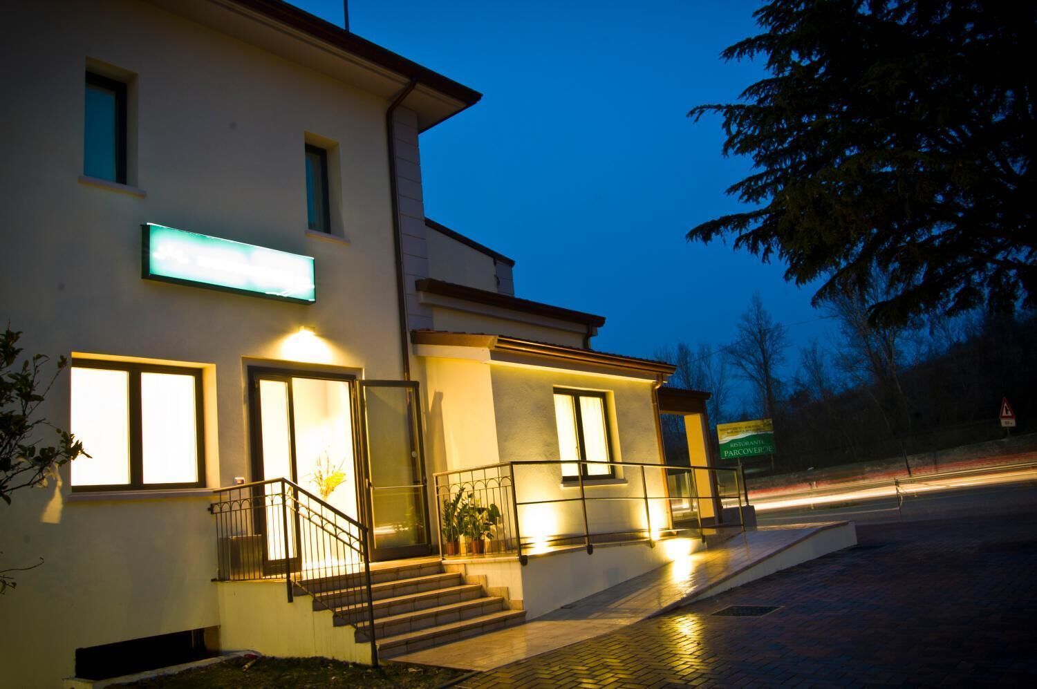 A modern building with a well-lit entrance, a staircase, and a sign indicating a restaurant.