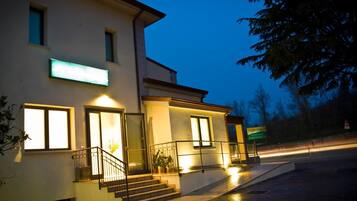 A modern building with a well-lit entrance, a staircase, and a sign indicating a restaurant.