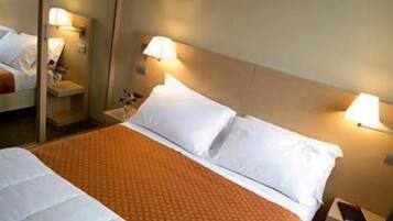 A hotel room with a large bed, two bedside lamps, and a nightstand with a lamp.