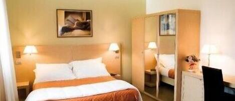 A hotel room with a bed, bedside tables, a mirror, and a desk.