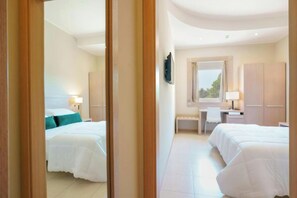 Habitació d'hotel amb dos llits, escriptori, cadira, televisió i armari.