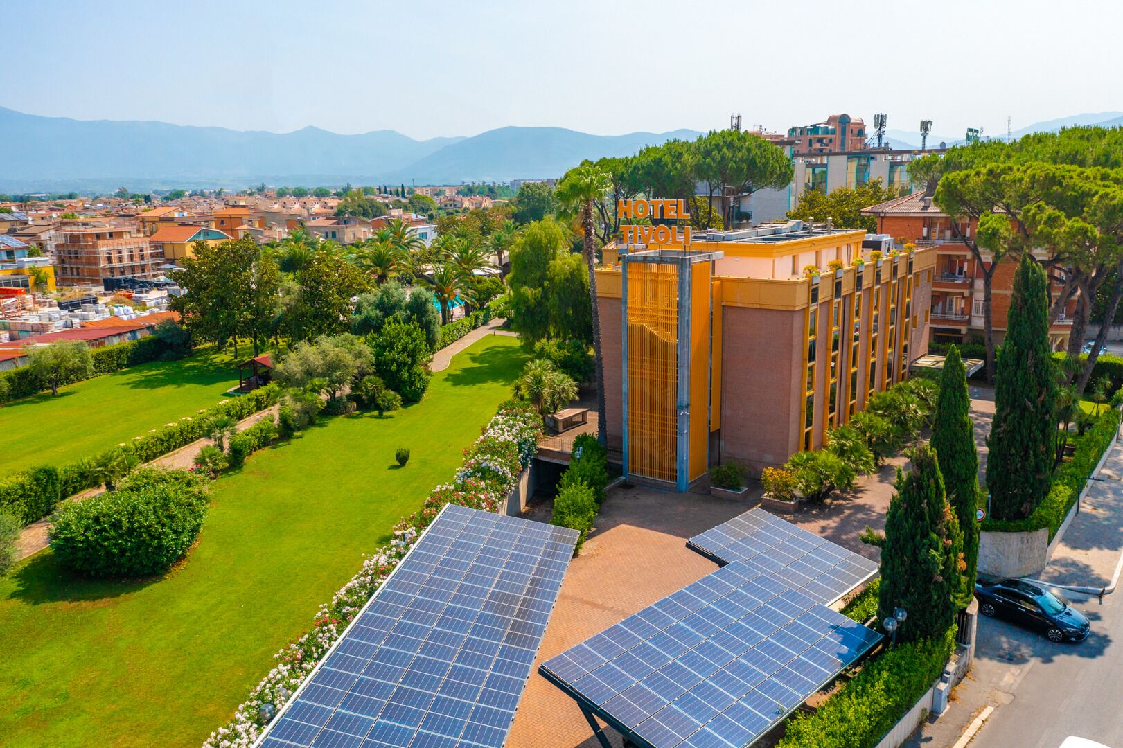Un hotel con jardín en la azotea, paneles solares y vistas a la ciudad y a las montañas.