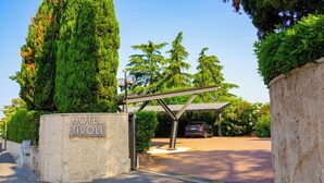 A hotel entrance with a sign reading "HOTEL TIVOLI," a covered parking area, and lush greenery. - Hotel Tivoli (Tivoli)