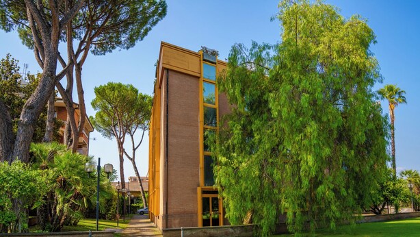 A modern building with a glass facade, surrounded by lush greenery and trees. - Hotel Tivoli (Tivoli)