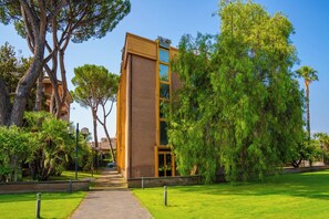 A modern building with a glass facade, surrounded by lush greenery and trees. - Hotel Tivoli (Tivoli)