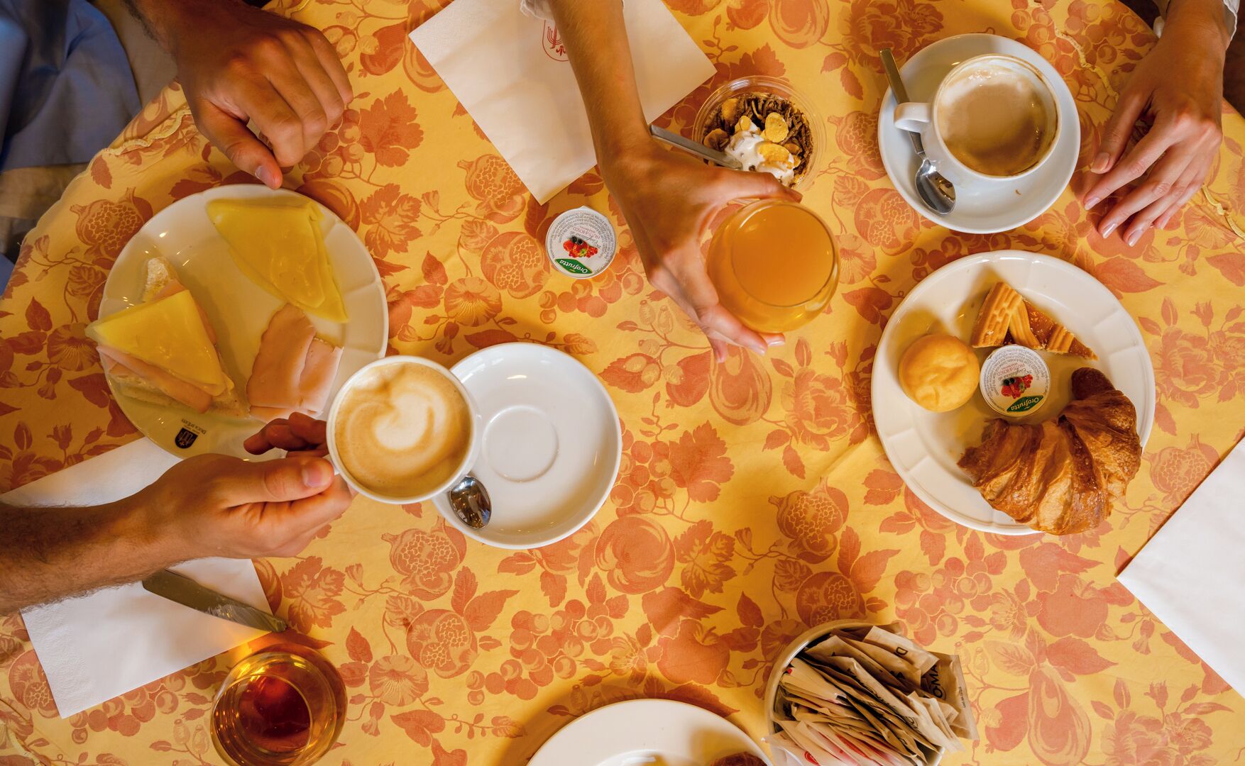 Una mesa con diferentes alimentos para el desayuno, como café, pasteles y un bol de fruta.