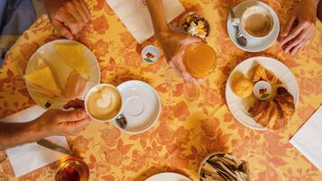 Una mesa con diferentes alimentos para el desayuno, como café, pasteles y un bol de fruta.