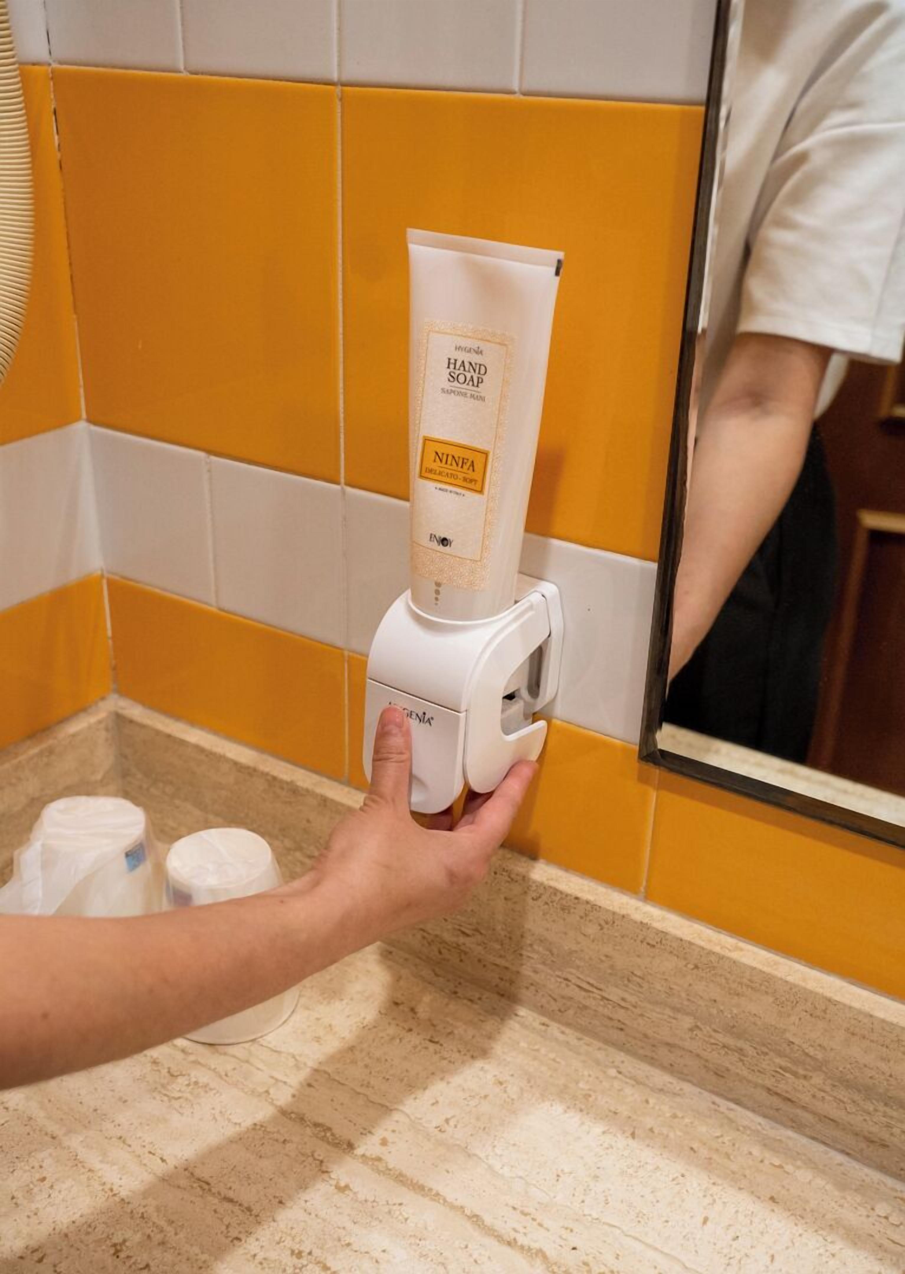 Un dispensador de jabón de manos en un baño con baldosas amarillas y blancas.