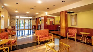 A lobby with wicker furniture, a glass coffee table, and a reception desk. - Hotel Tivoli (Tivoli)