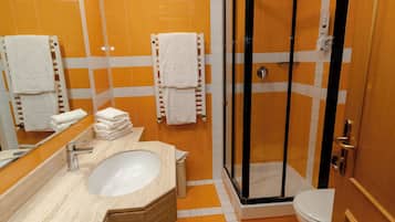 A bathroom with a sink, mirror, and a glass-enclosed shower.