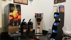 A coffee station with a Fruit Juice machine, a Donut Shop dispenser, and a coffee machine.
