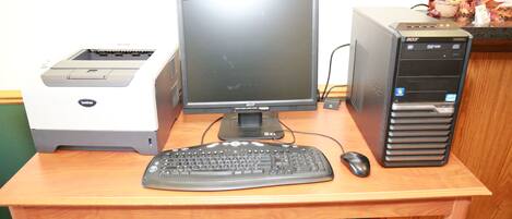 A wooden desk with a desktop computer, keyboard, and mouse.