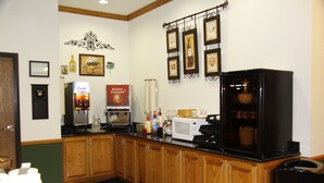 A kitchen with wooden cabinets, a black refrigerator, a microwave, and a coffee machine.