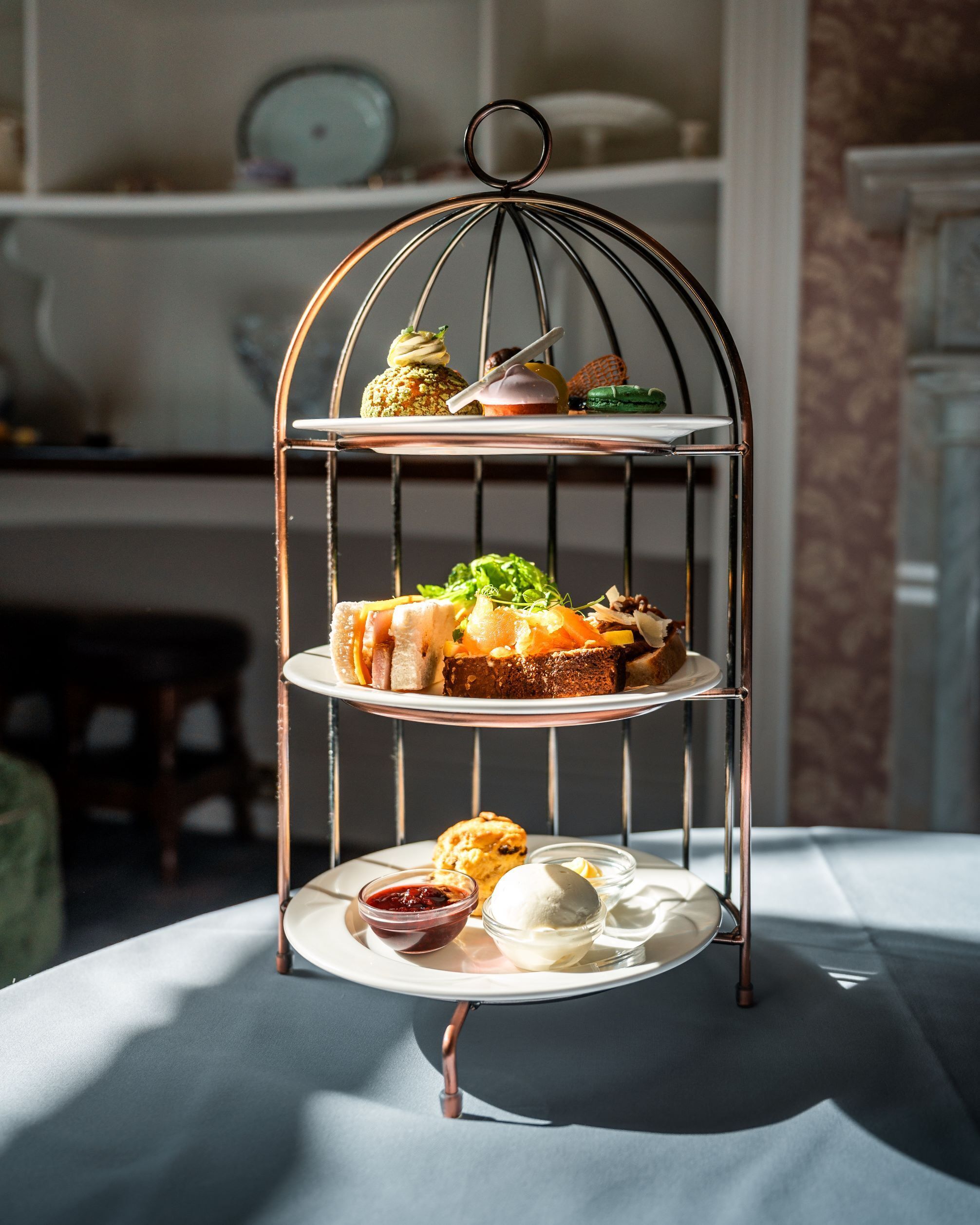 A three-tiered metal dessert stand with various pastries and desserts on each tier.