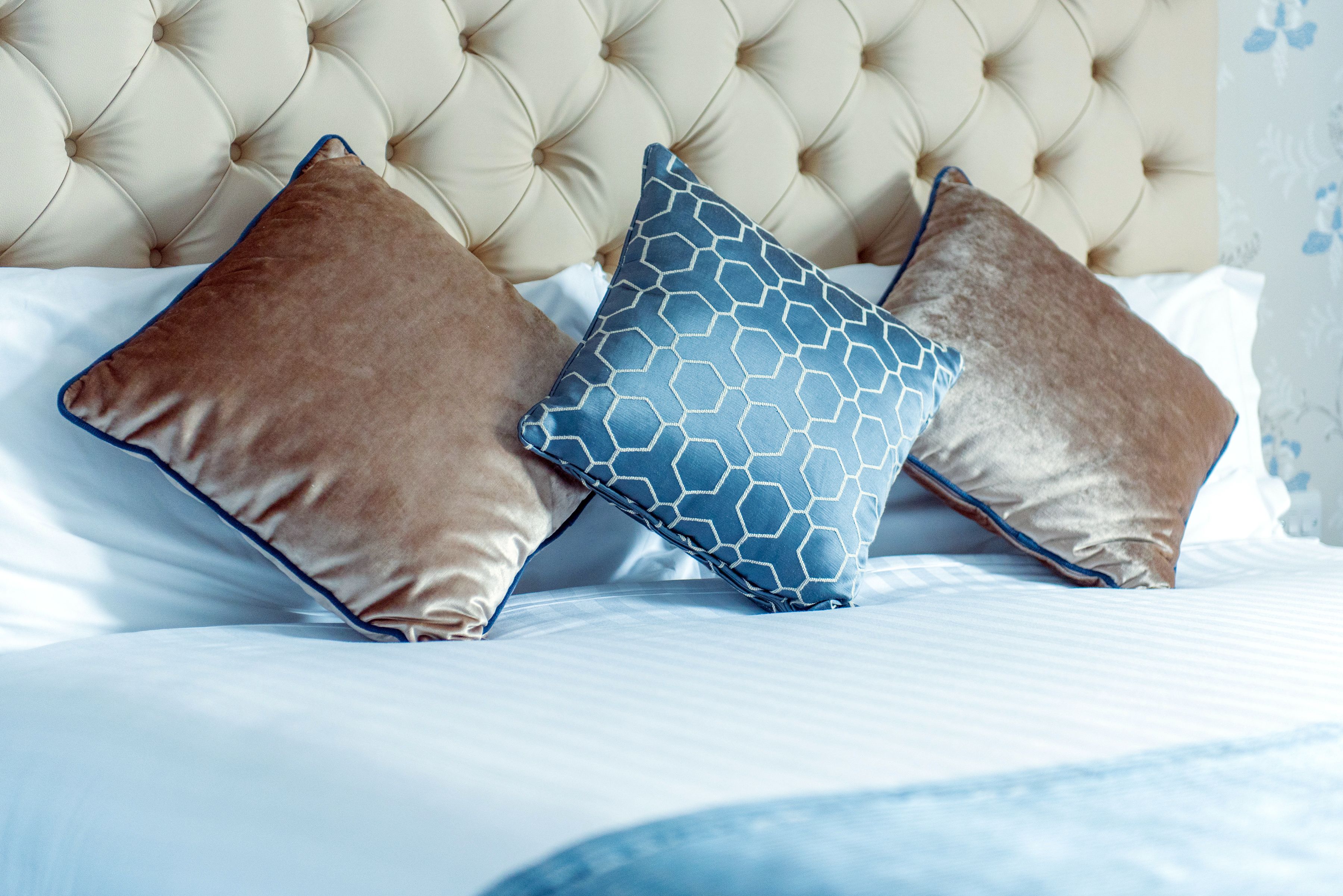 Una cama con cabecera capitonada y tres almohadas.