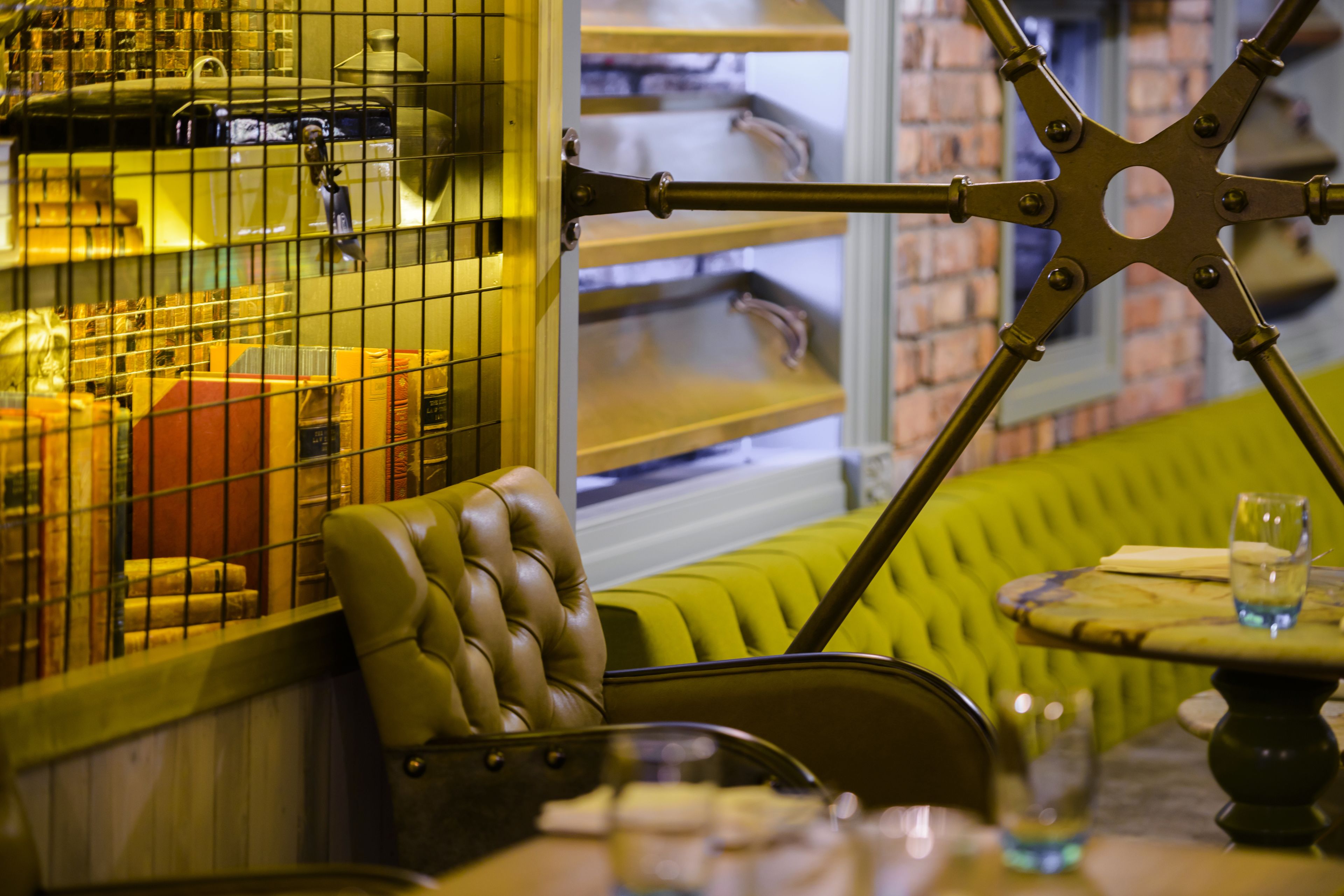 A restaurant interior with a booth seating area, a bar counter, and a brick wall in the background.