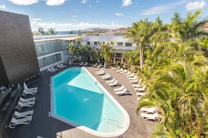 A rooftop pool area with lounge chairs and palm trees. - R2 Bahía Playa Design Hotel & Spa Wellness - Adults Only (Tuineje)