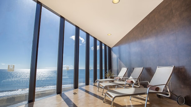 A modern hotel room with large windows offering a sea view, a sun lounger, and a potted plant. - R2 Bahía Playa Design Hotel & Spa Wellness - Adults Only (Tuineje)