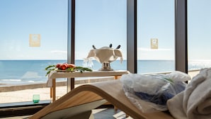 A room with a view of the beach, a table with a decorative item, and a bed with a plastic bag. - R2 Bahía Playa Design Hotel & Spa Wellness - Adults Only (Tuineje)