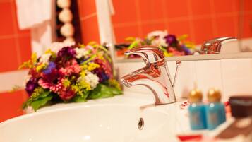 A bathroom sink with a modern faucet, a mirror, and a bouquet of flowers.