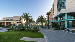 A modern building with a glass facade, palm trees, and a paved walkway. - Victoria Terme Hotel (Tivoli)