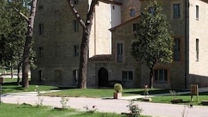 Un bâtiment en pierre doté d’une cour intérieure, entouré d’arbres et d’une pelouse bien entretenue.