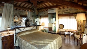 Une chambre à coucher avec un lit, un miroir, une commode, une chaise, une table et une fenêtre avec des rideaux.