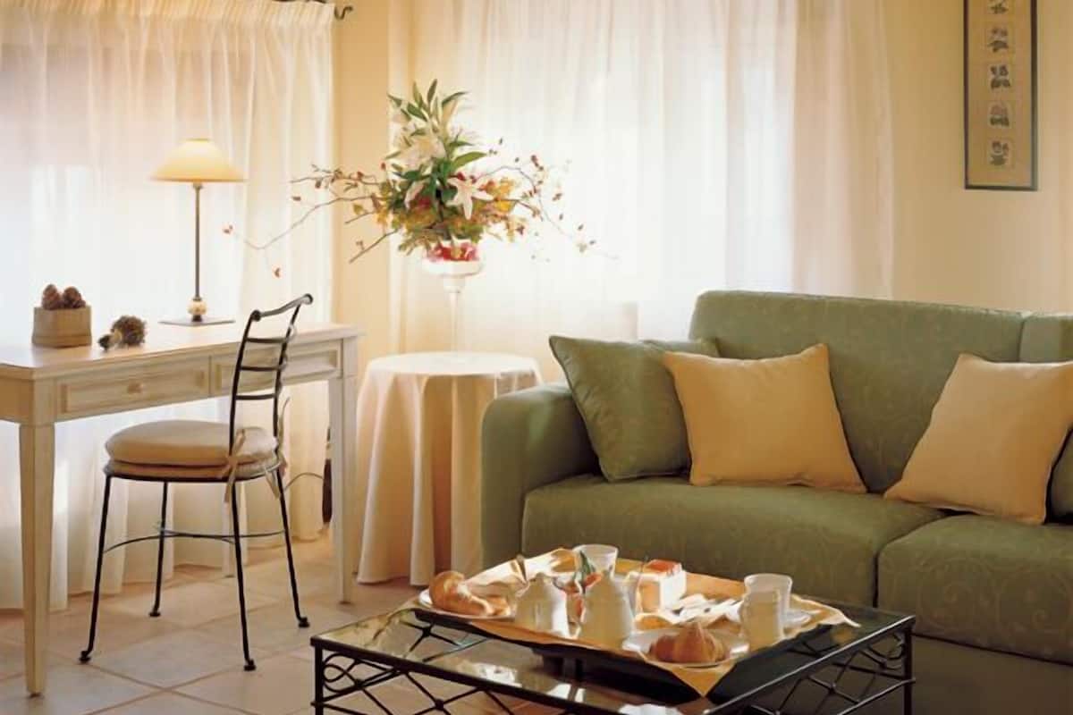 Un salon chaleureux avec un canapé vert, une table à manger avec des chaises et une table basse sur laquelle sont disposés des aliments.