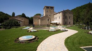 Une cour avec un chemin pavé de pierres, une piscine et un bâtiment doté d’une tour.