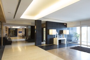 Un vestíbulo moderno con mostrador de recepción, zona de estar y ventanas amplias.