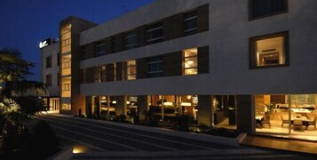 Un hotel moderno de dos plantas, con amplios ventanales y un área de entrada bien iluminada.